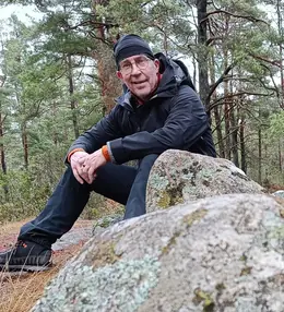 Erik Astrand sitting on a rock in a Nordic pine forest.